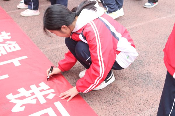 学生在班级横幅上签上自己的名字.JPG