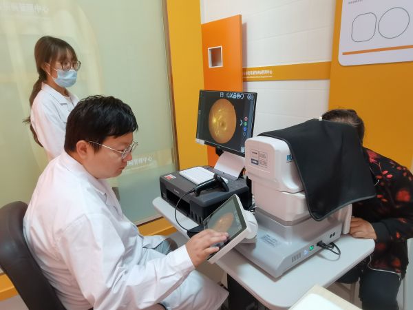 图为十二团医院眼科门诊医生为老年人眼病患者诊断检查。.jpg