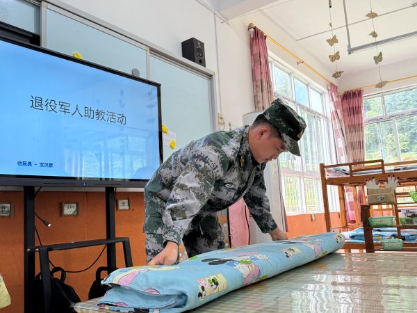 图为  退役军人志愿者向学生们示范“豆腐块”被子的折叠现场（许青青  摄）.jpg
