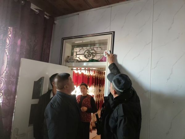 民警调试群众家中的烟感报警器，为户主讲解设备的使用注意事项。杨宇豪摄.jpg