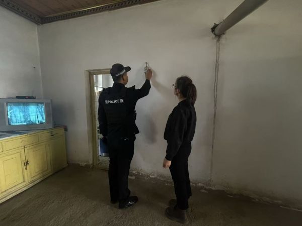 民警在群众家中检查烟感报警器的运行状态，一边调试设备，一边向身旁群众讲解报警器的作用与日常维护要点。敬浩龙摄.jpg