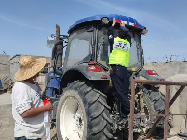 警务人员给农用机器贴反光贴.jpg