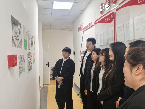 05261779801860275911.jpg 图为职工正在参观小朋友们的微画展-金雯晴摄.jpg